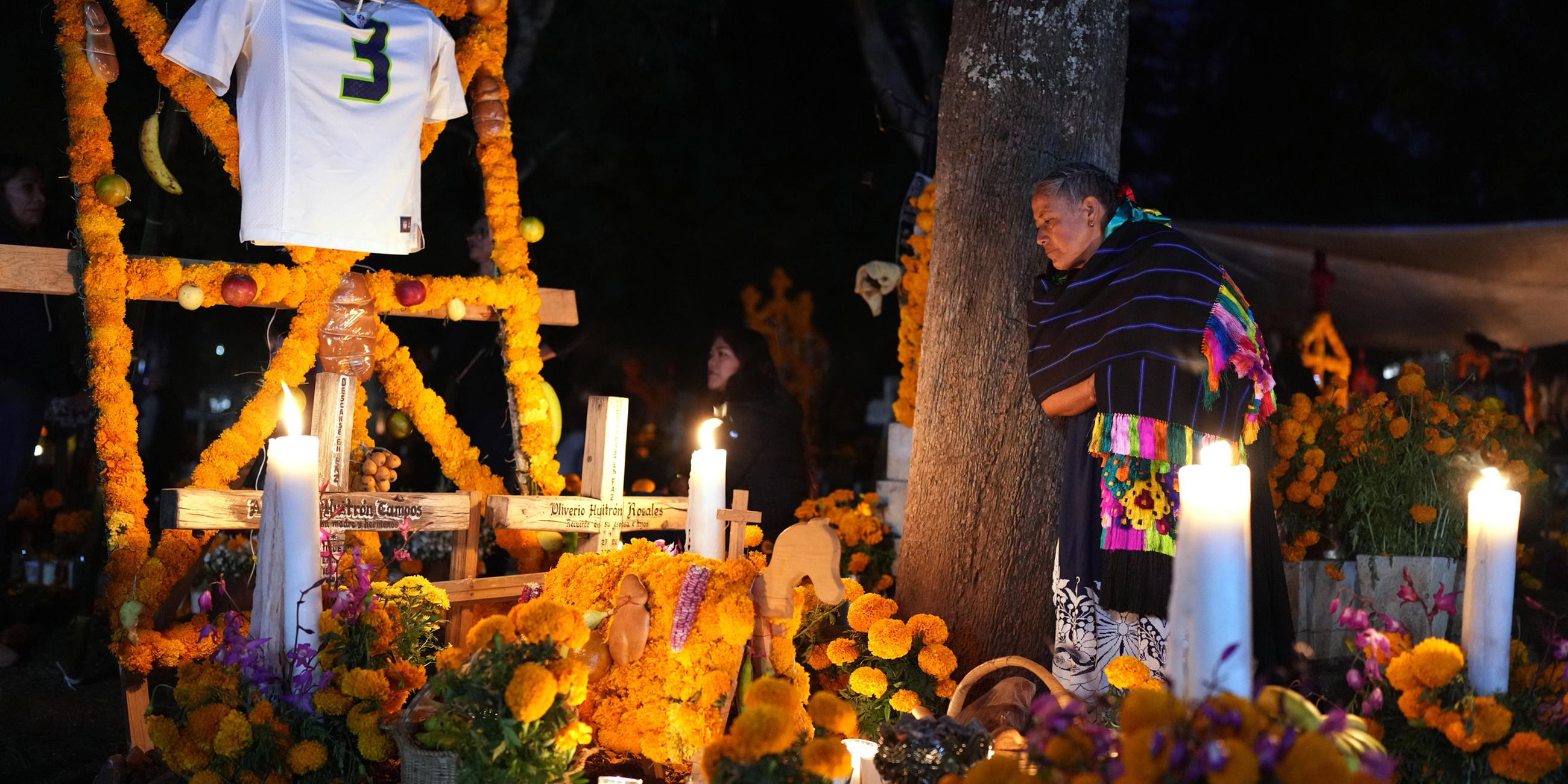 Eine Frau steht neben dem Grab eines geliebten Menschen und feiert den Tag der Toten auf dem Friedhof von Tzintzuntzan im Bundesstaat Michoacán, Mexiko, am Freitag, 31. Oktober 2025. 