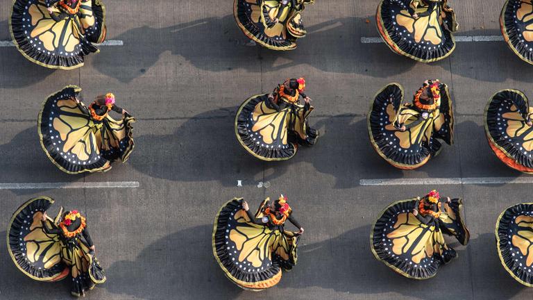 Menschen in Kleidern tanzen bei der Parade zum Tag der Toten in Mexiko City.