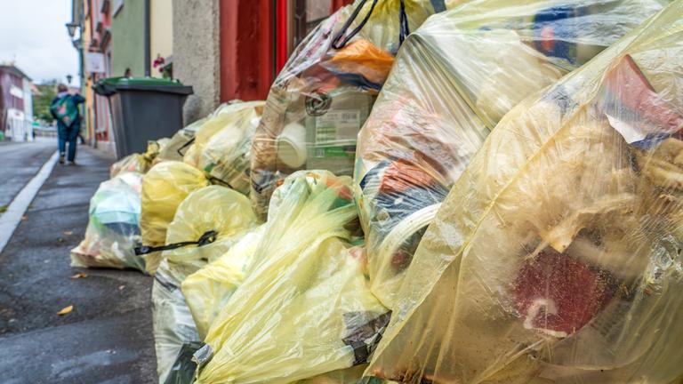 Viele Gelbe Säcke liegen am Straßenrand.
