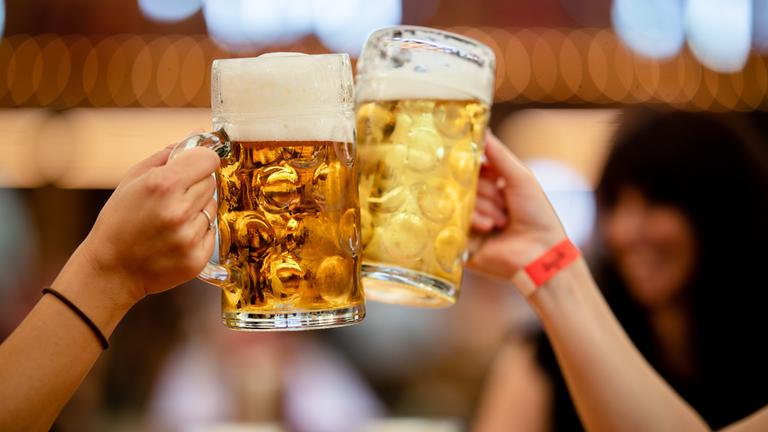 Besucher des 85. Stuttgarter Frühlingsfests stoßen in einem Festzelt mit zwei Mass Bier an.