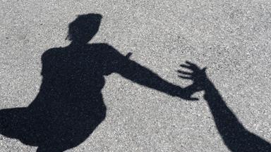 Männlicher Schatten greift nach weiblichem Schatten