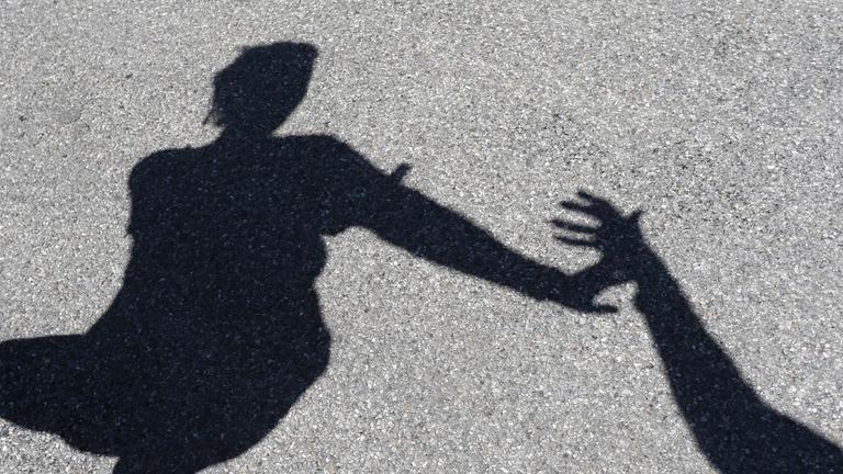 Männlicher Schatten greift nach weiblichem Schatten