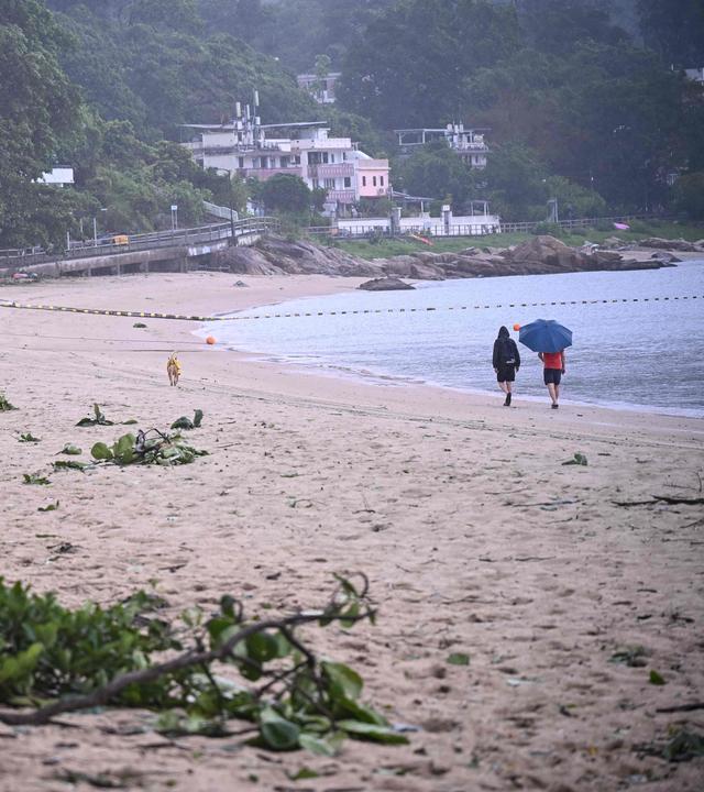 Menschen gehen an einem Strand in Hongkong an Trümmerteilen vorbei, die der Taifun „Noul“ nach seinem Vorbeizug hinterlassen hat.