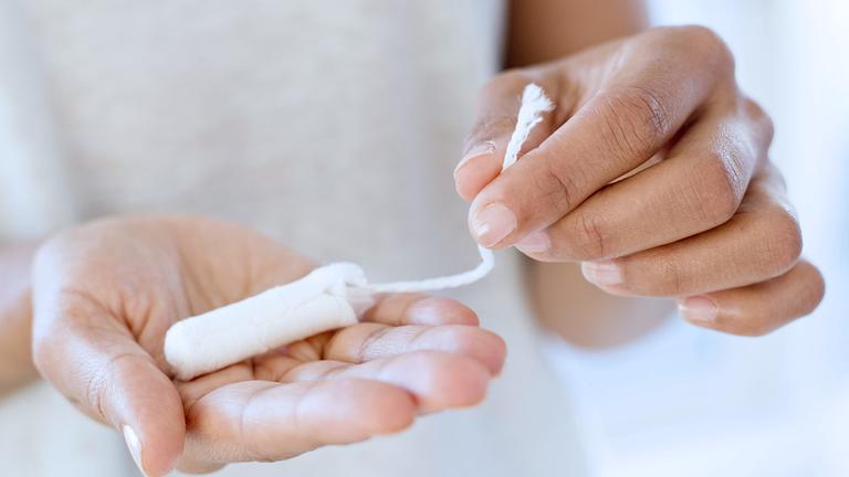 Eine Fau hält einen Tampon in der Hand