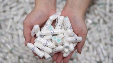 Eine Produktionsarbeiterin hält Tampons in ihren Händen.