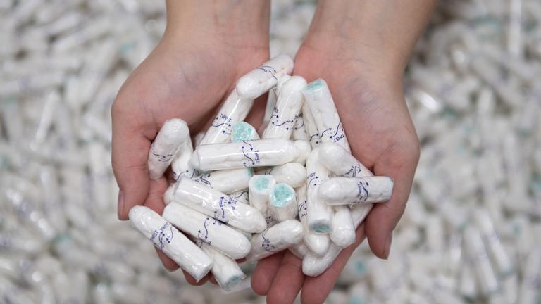 Eine Produktionsarbeiterin hält Tampons in ihren Händen.