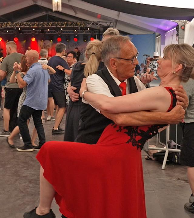 Paare tanzen Tango auf der Tanzfläche vor einer Bühne