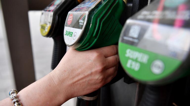 Eine Frau greift nach der Zapfpistole an einer Tankstelle.