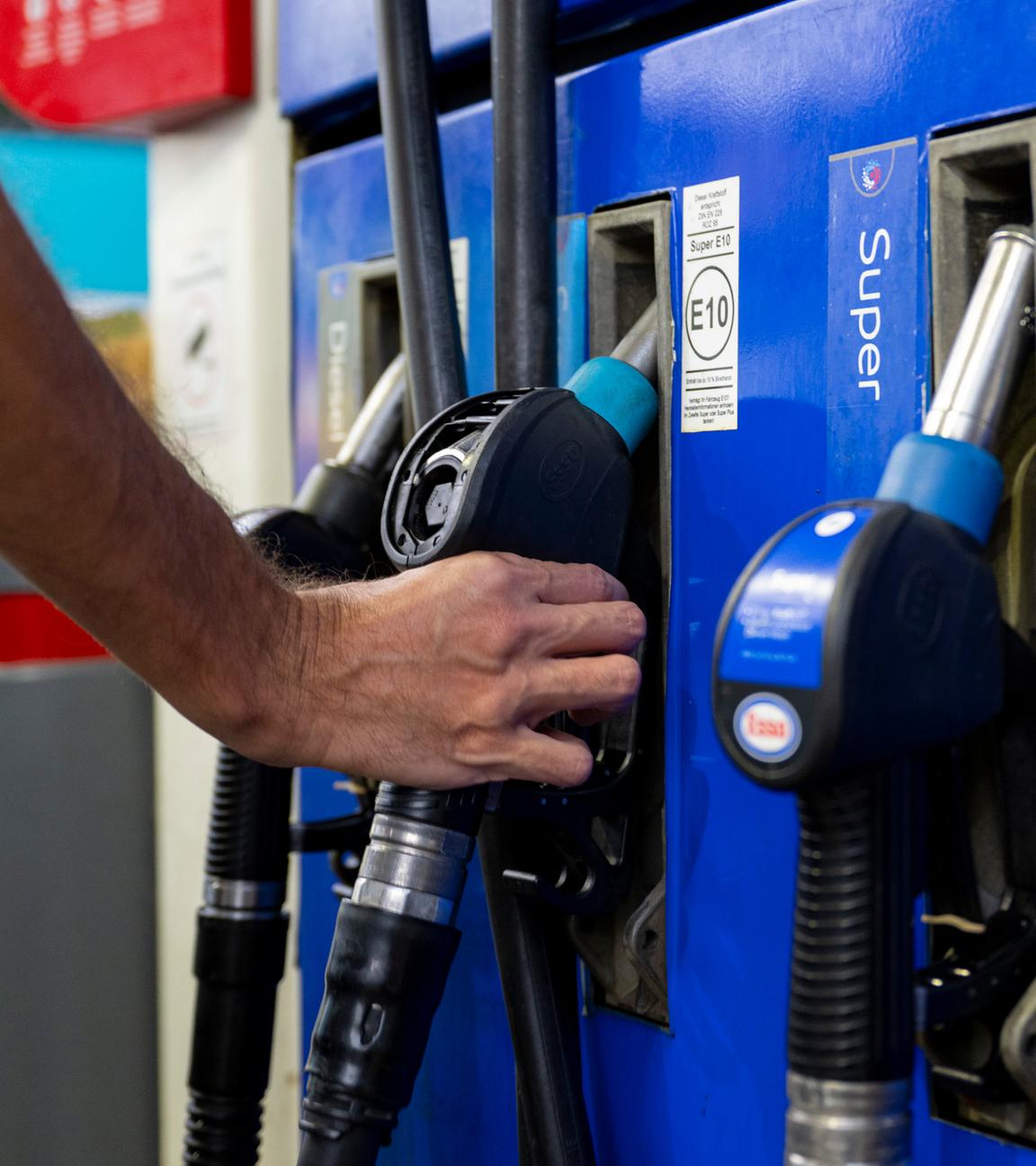 Symbolbild: Ein Autofahrer hängt an einer Tankstelle eine Zapfpistole in die Zapfsäule.