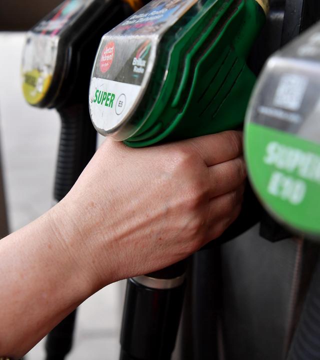 Symbolbild: Eine Frau greift nach der Zapfpistole an einer Tankstelle. 