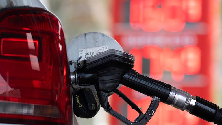 Ein Tankstutzen steckt an einer Tankstelle in der Tanköffnung eines Fahrzeugs.