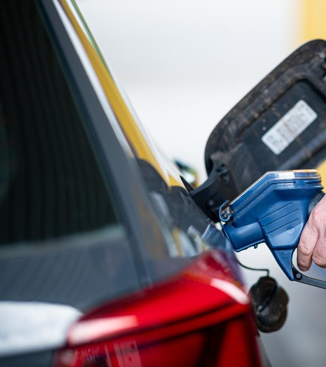 Ein Mann betankt an einer Tankstelle sein Auto. 