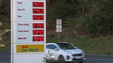 Symbolbild: Tankstelle, Stehle mit Anzeige der Spritpreise und ein fahrendes Auto