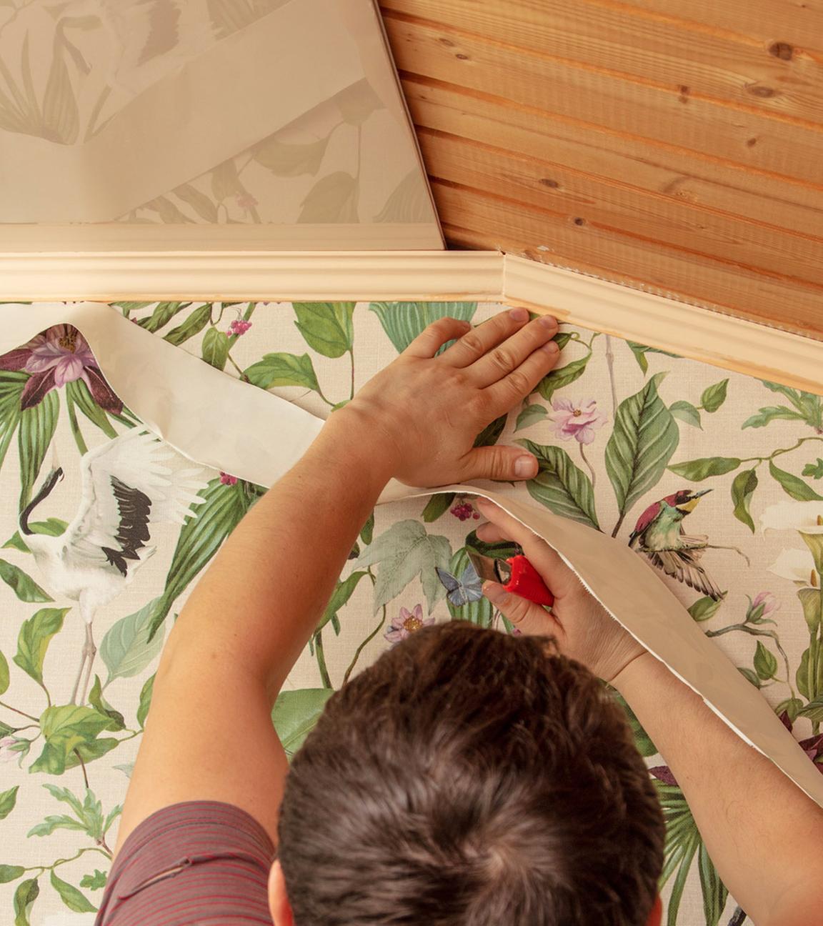 Mann tapeziert Wand mit bunter Tapete