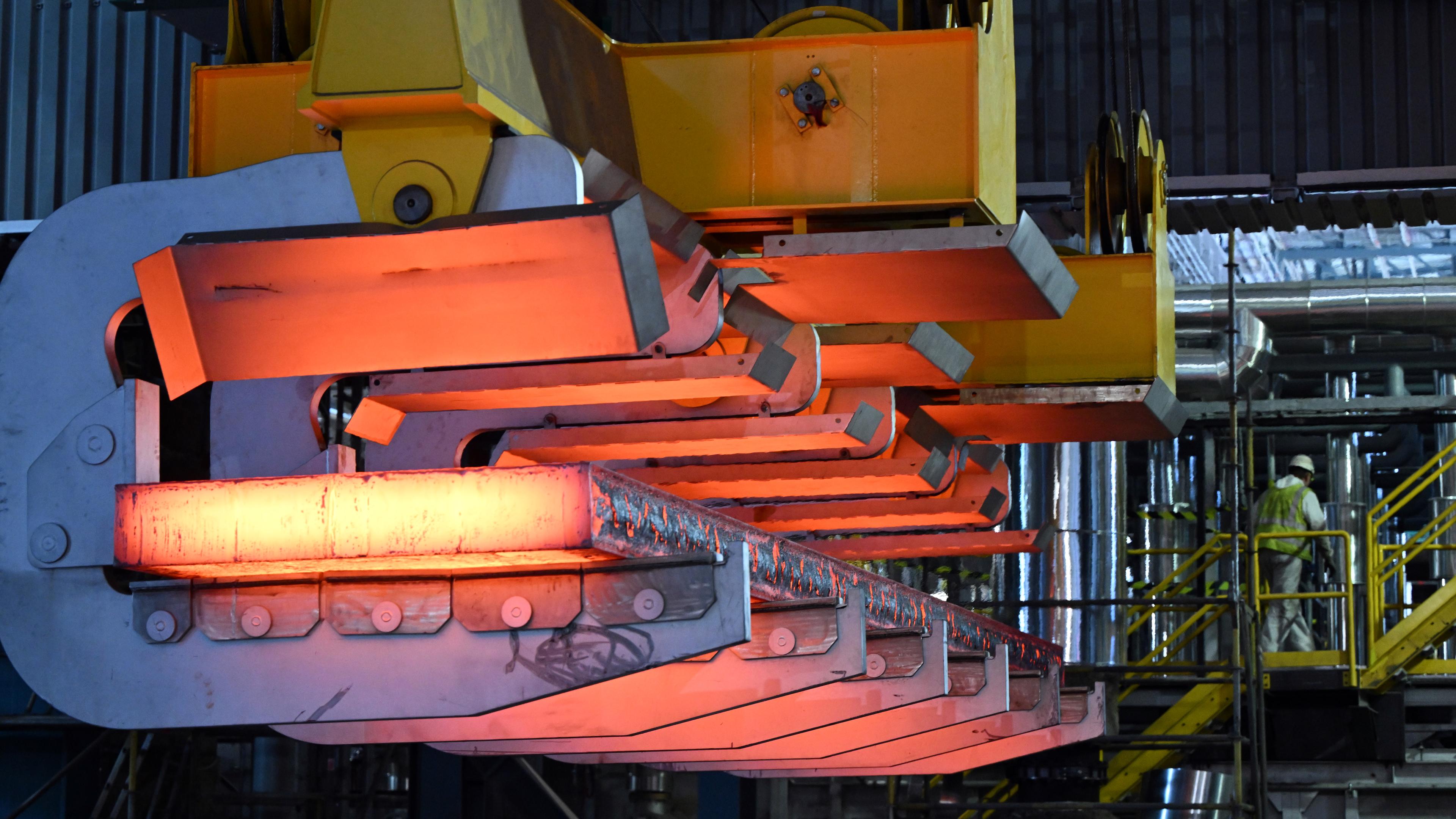 Eine glühende Bramme wird mit einem Kran aus der Stranggießanlage bei Thyssenkrupp Steel transportiert.