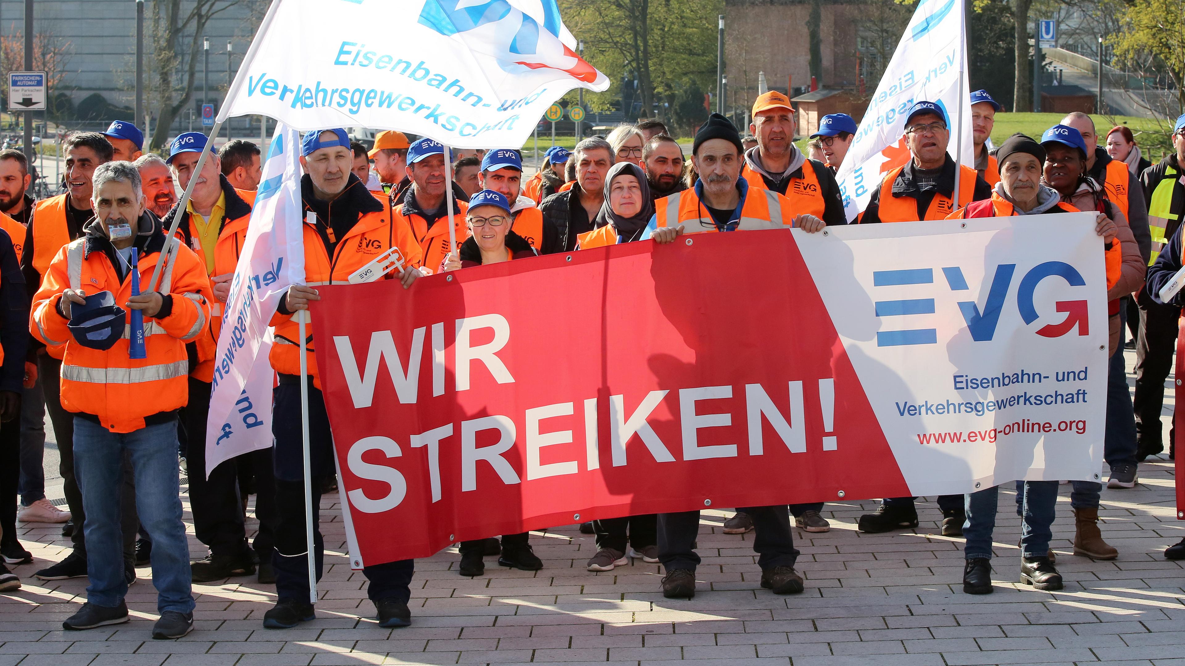 Warnstreikende der Gewerkschaft EVG bei einer Kundgebung in Hamburg halten Fahnen und Banner.