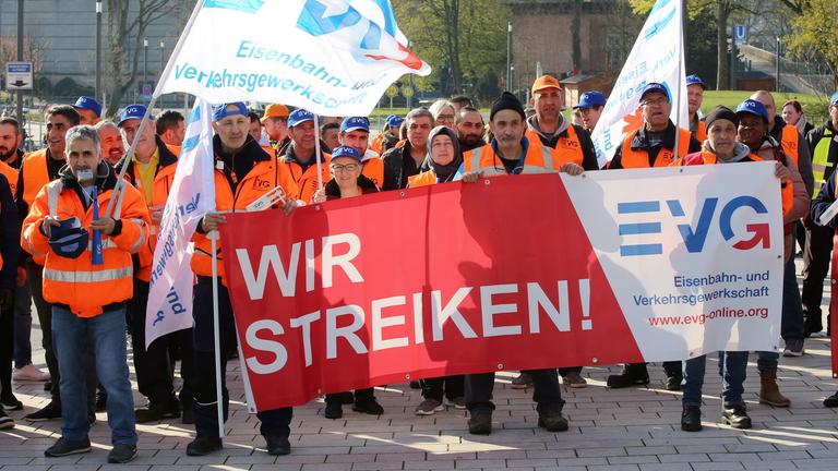 Warnstreikende der Gewerkschaft EVG bei einer Kundgebung in Hamburg halten Fahnen und Banner.