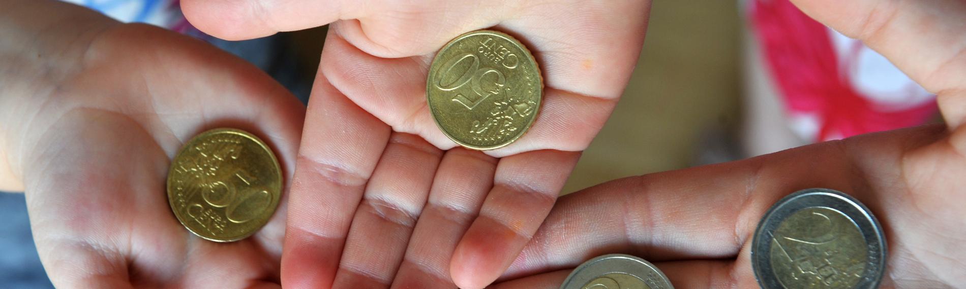 Drei Hände halten Münzen. 