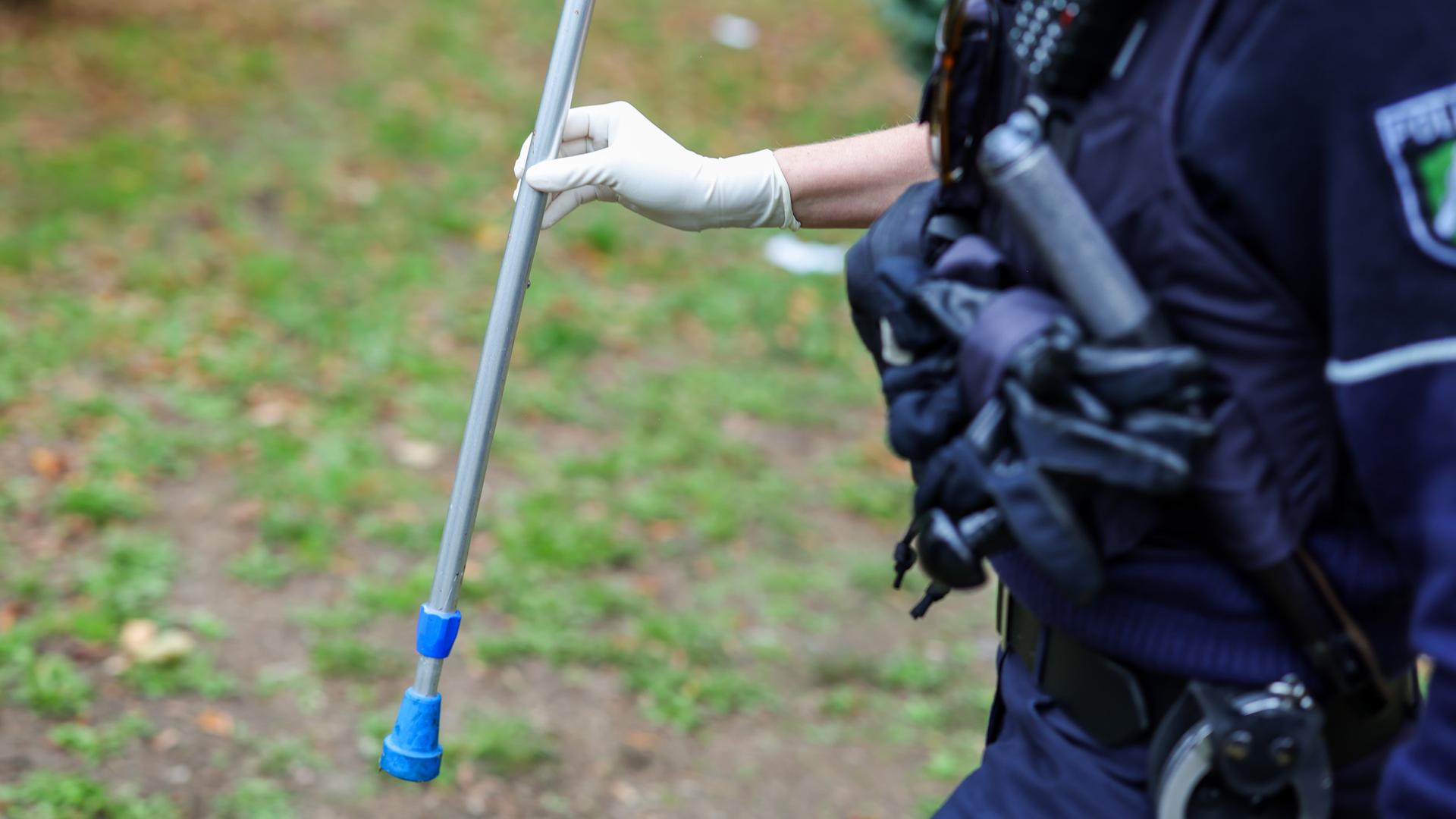  Eine Polizeibeamtin hält ein Beweismittel in der Hand, die Hälfte einer Krücke, die bei der Massenschlägerei eingesetzt worden war.
