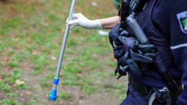  Eine Polizeibeamtin hält ein Beweismittel in der Hand, die Hälfte einer Krücke, die bei der Massenschlägerei eingesetzt worden war.