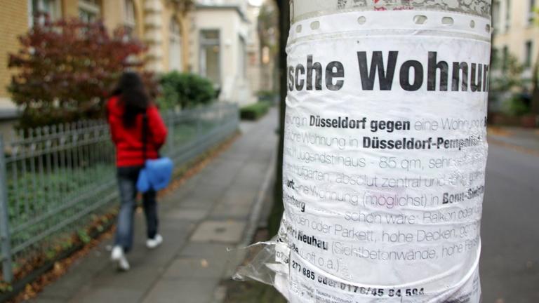 An einem Laternenpfahl hängt ein Tauschgesuch für eine Mietwohnung.