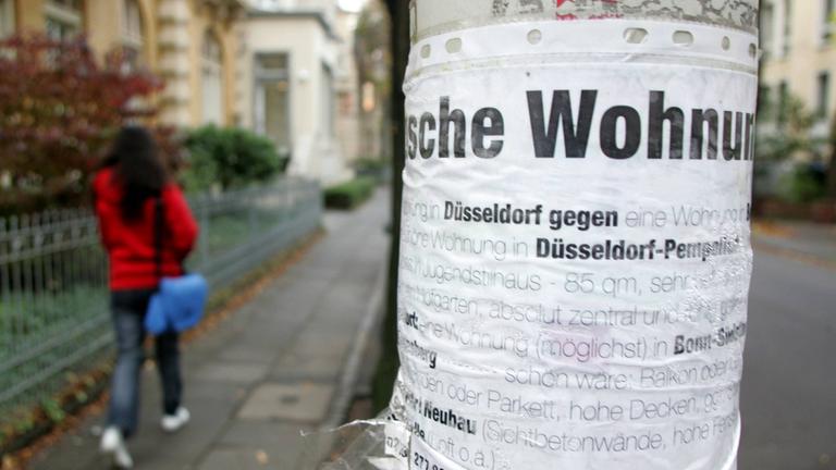 An einem Laternenpfahl hängt ein Tauschgesuch für eine Mietwohnung.