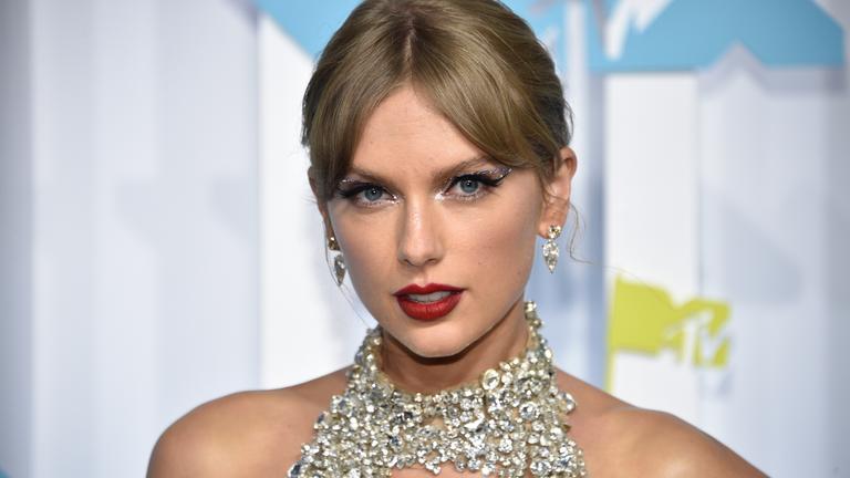 Portraitfoto der stark geschminkten Sängerin Taylor Swift in silberfarbenem Glitzerkleid. 