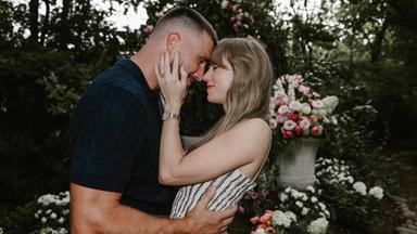 Taylor Swift und Travis Kelce stehen sich in einem blumenreichen Garten gegenüber und halten sich im Arm.