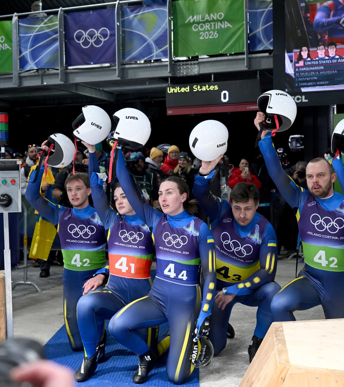 Das Team der Ukraine kniet am Boden und hebt im Zielbereich gemeinsam die Helme nach oben.