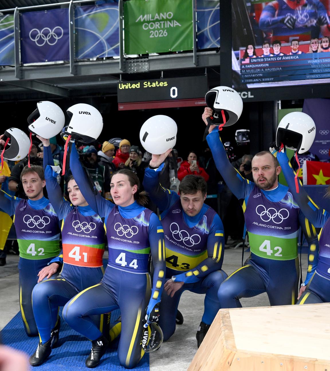Das Team der Ukraine kniet am Boden und hebt im Zielbereich gemeinsam die Helme nach oben.