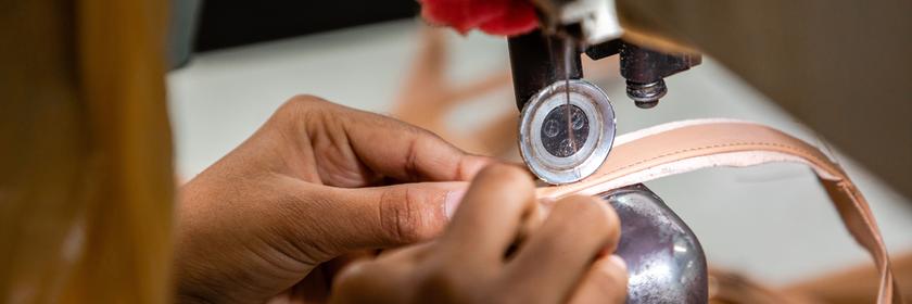 Großaufnahme von Händen, die an einer Nähmaschine nähen.