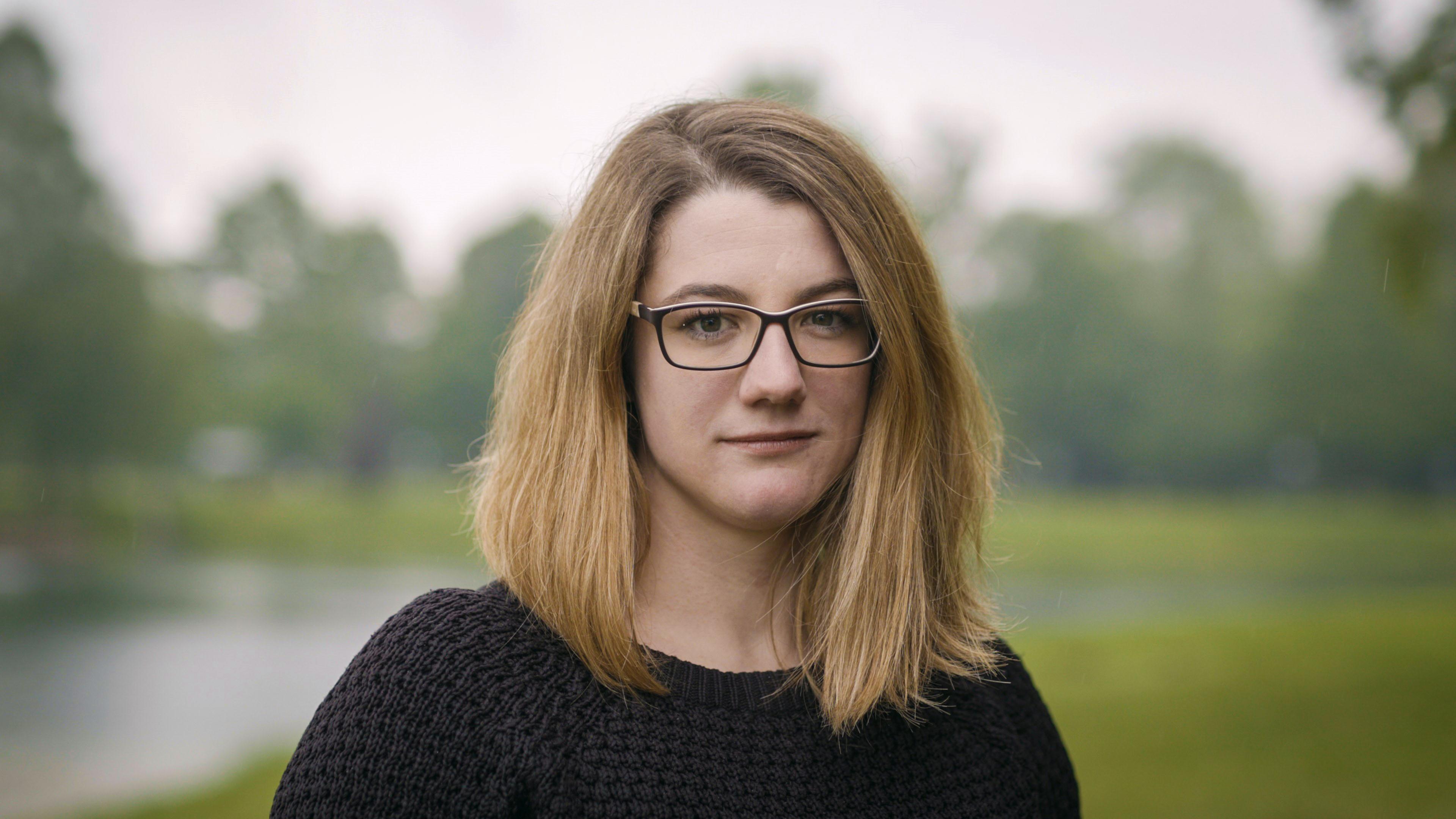 Eine junge vor einem See. Es ist Corinne, die seit ihrer Geburts mit Aids infiziert ist.
