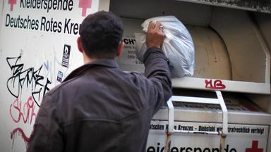 Mann wirft Kleidung in Altkleidercontainer