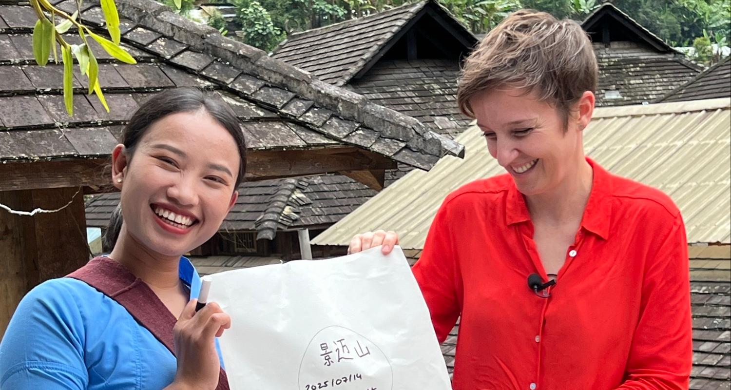 Xian Jin steht neben Miriam Steimer und sie halten gemeinsam ein Papier hoch.