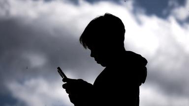 Symbolbild: Jugendlicher mit Smartphone im Schattenriss
