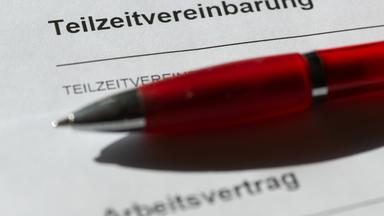Ein roter Kugelschreiber liegt auf einer Teilzeitvereinbarung sowie einem Arbeitsvertrag