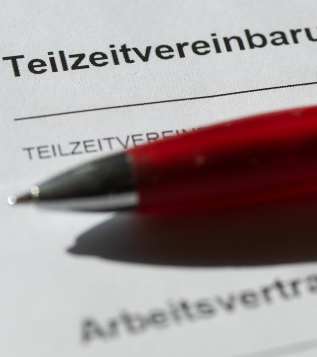 Ein roter Kugelschreiber liegt auf einer Teilzeitvereinbarung sowie einem Arbeitsvertrag