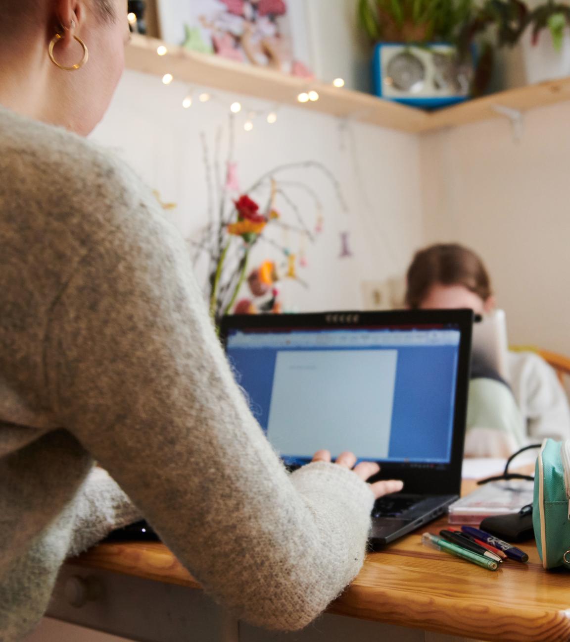 29.04.2021, Berlin: Eine Mutter arbeitet am Küchentisch während ihre Tochter gegenüber in ein Tablet guckt.