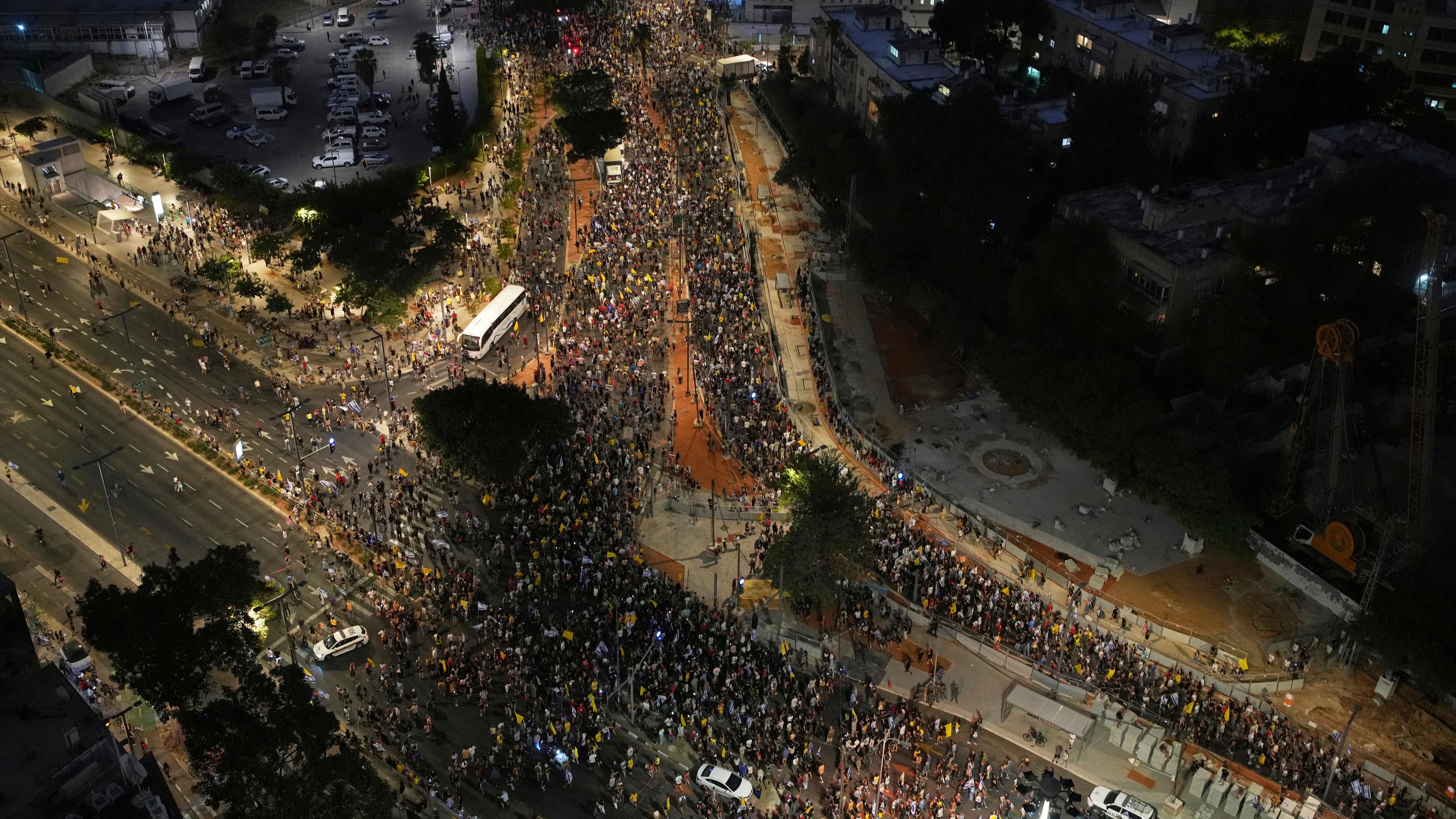 Eine Luftaufnahme bei Nacht der Straßen von Tel Aviv, die mit Tausenden Demonstranten gefüllt sind.