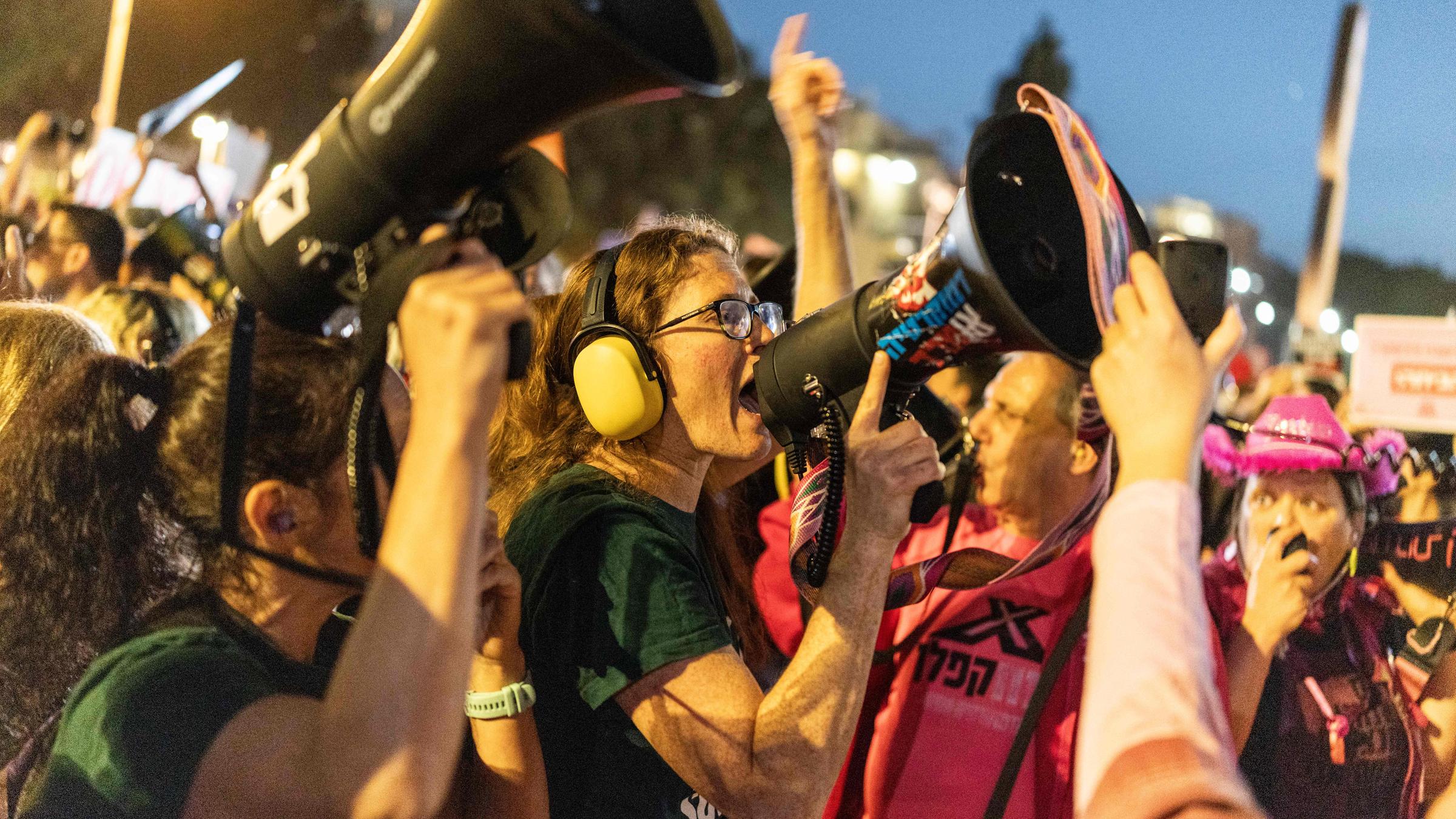 Israelische Aktivisten bei einer Demonstration gegen den andauernden Krieg mit dem Iran, eine Frau ruft etwas in ein Megafon.