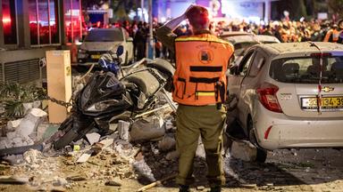 Israelische Polizeibeamte und Rettungskräfte arbeiten am Tatort eines Wohnhauses am Stadtrand von Tel Aviv, das von einer iranischen Rakete getroffen wurde. 