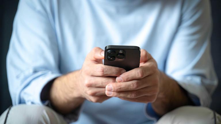Ein Mann tippt auf einem Smartphone.