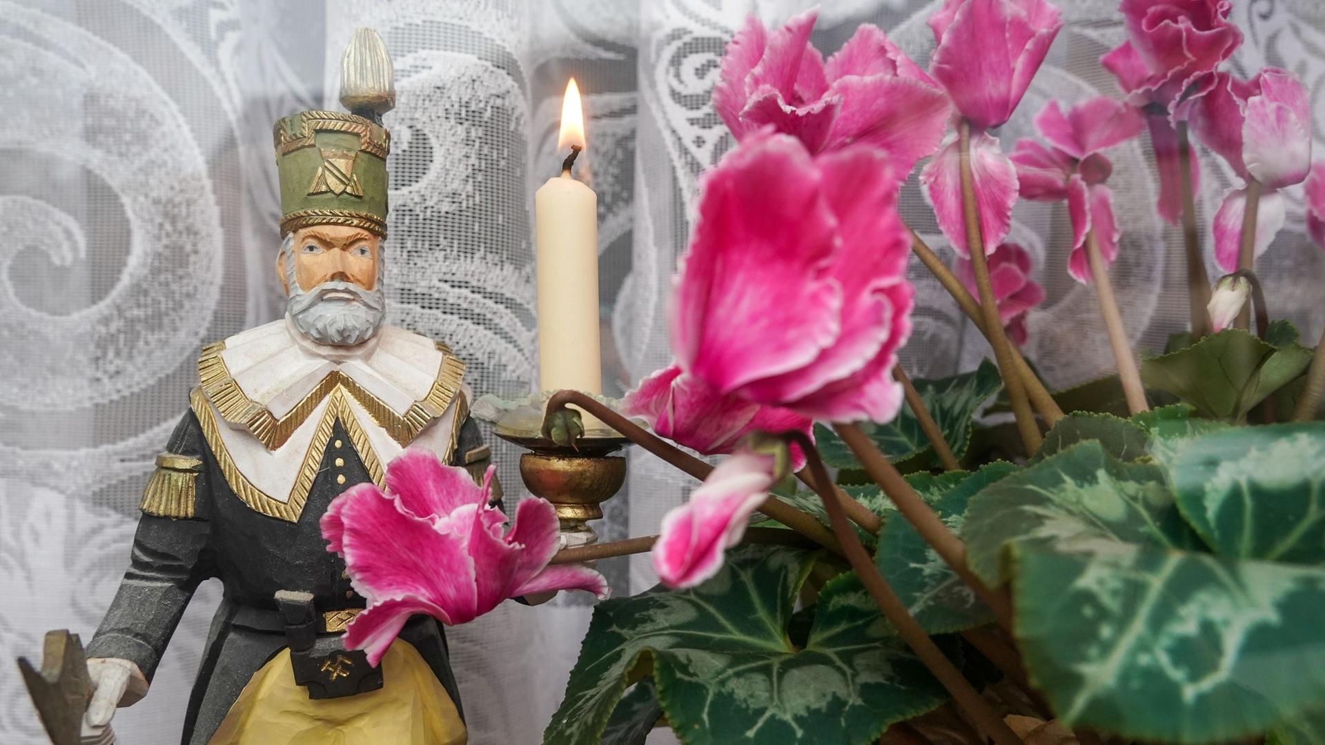 Alpenveilchen stehen neben einer Bergmannsfigur. Symbolbild