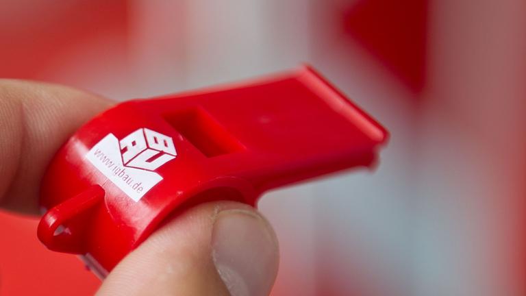 Das Logo der IG Bau auf einer Trillerpfeife. Symbolbild