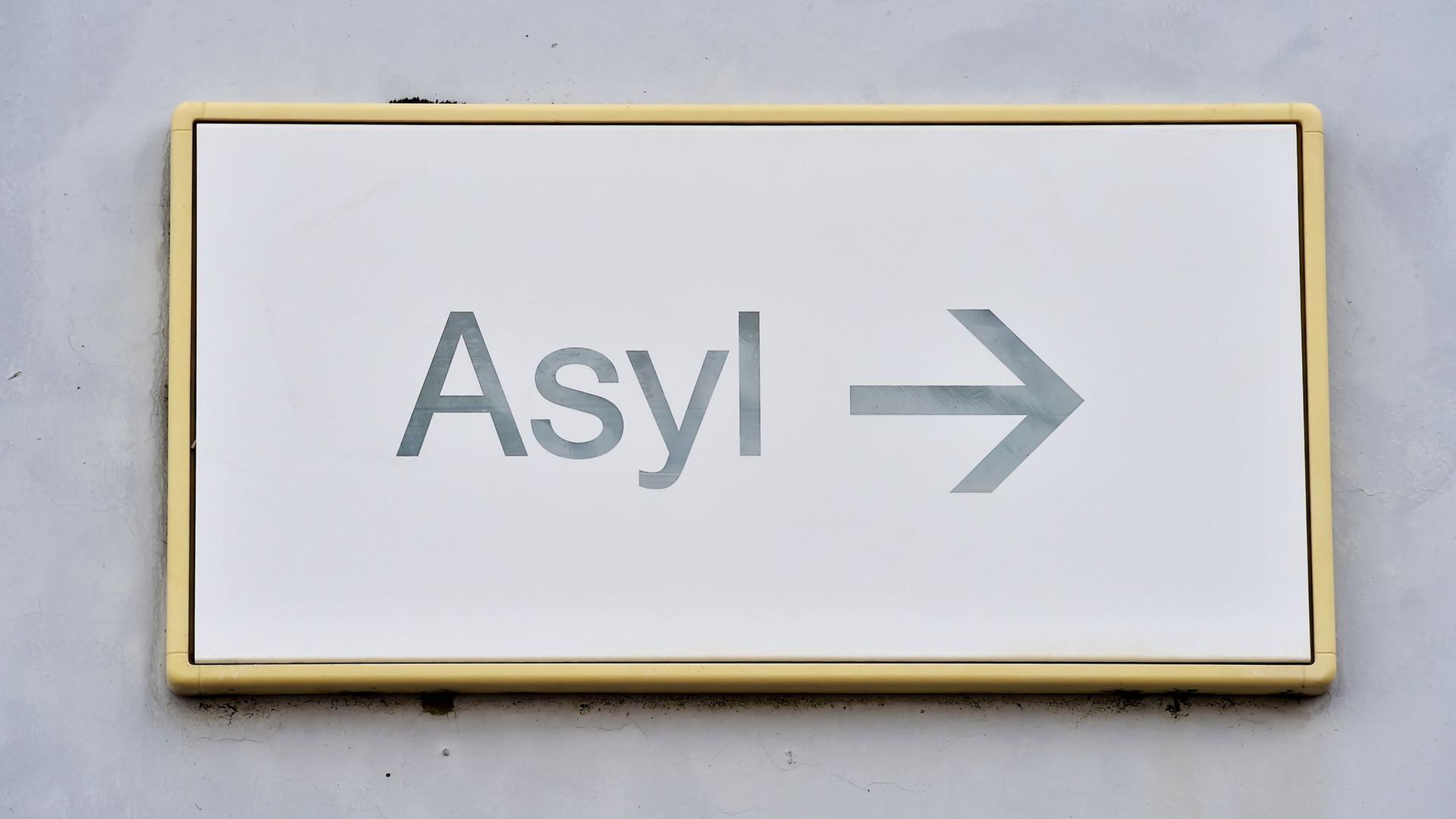 Auf einem Schild "Asyl" weist ein Pfeil Flüchtlingen den Weg zur Stelle für Asylanträge.