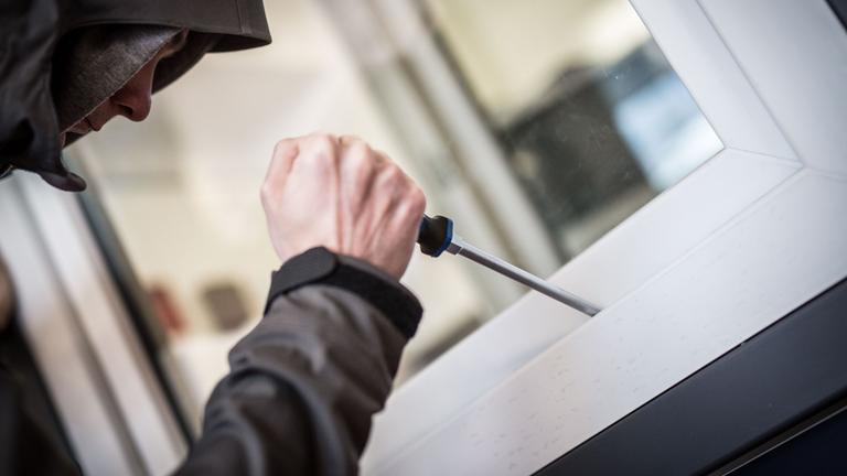 Ein Mann macht sich an einem Fenster zu schaffen. Symbolbild