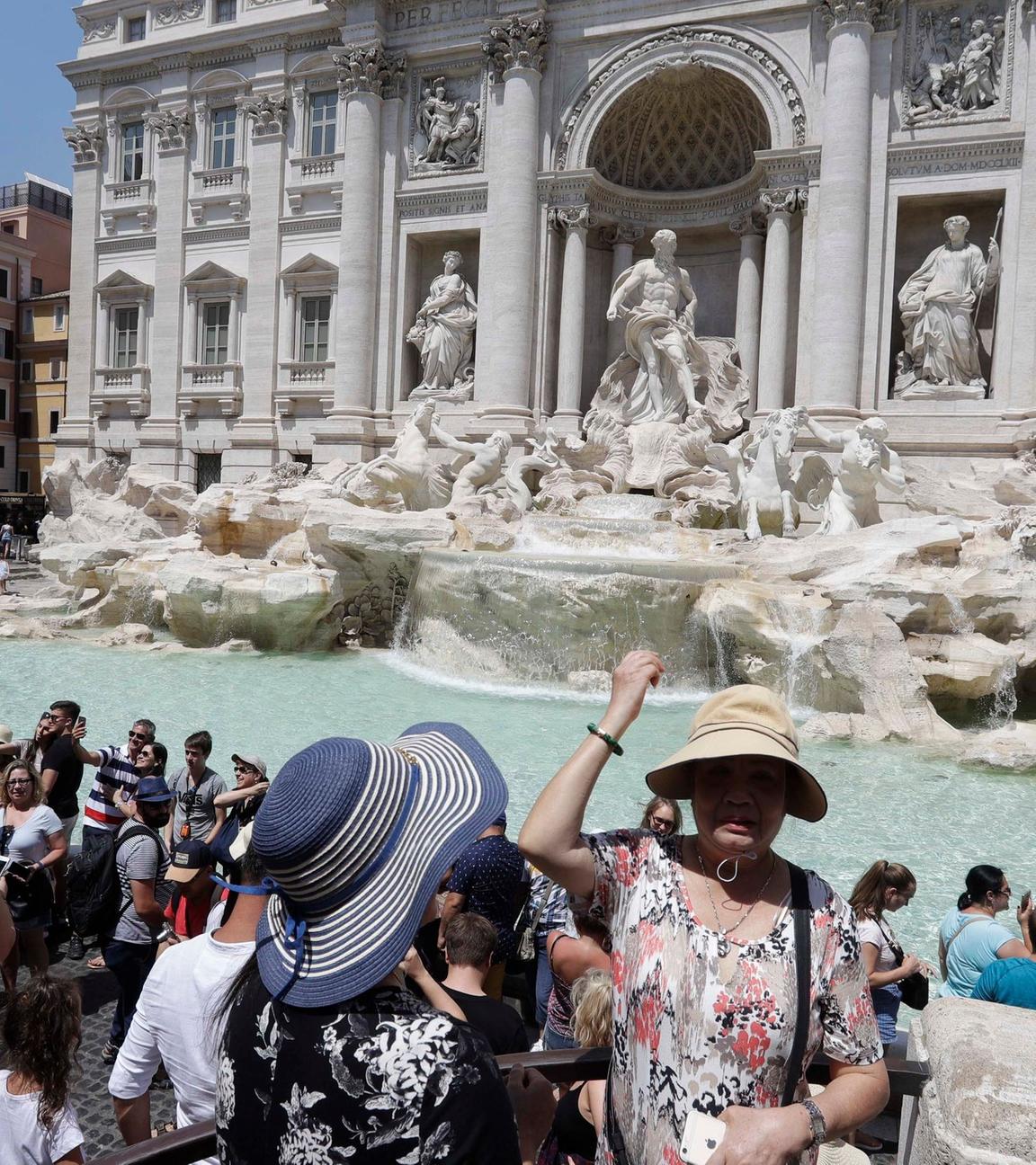 Eine Touristin  wirft eine Münze in den Trevi-Brunnen. Symbolbild