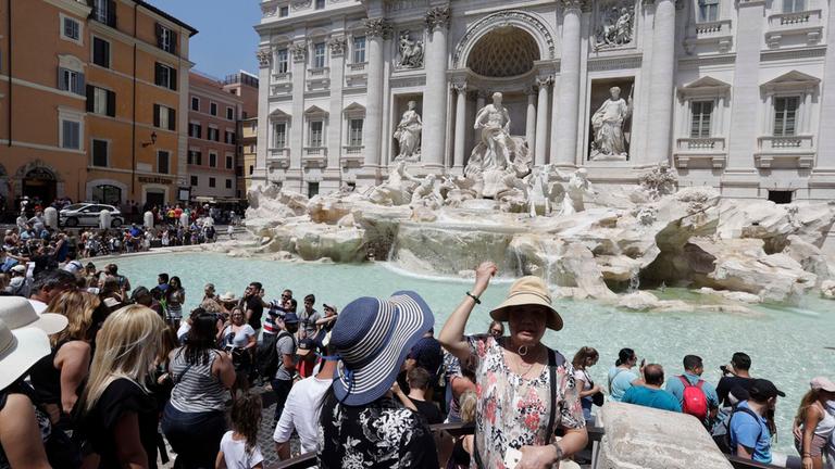 Eine Touristin  wirft eine Münze in den Trevi-Brunnen. Symbolbild