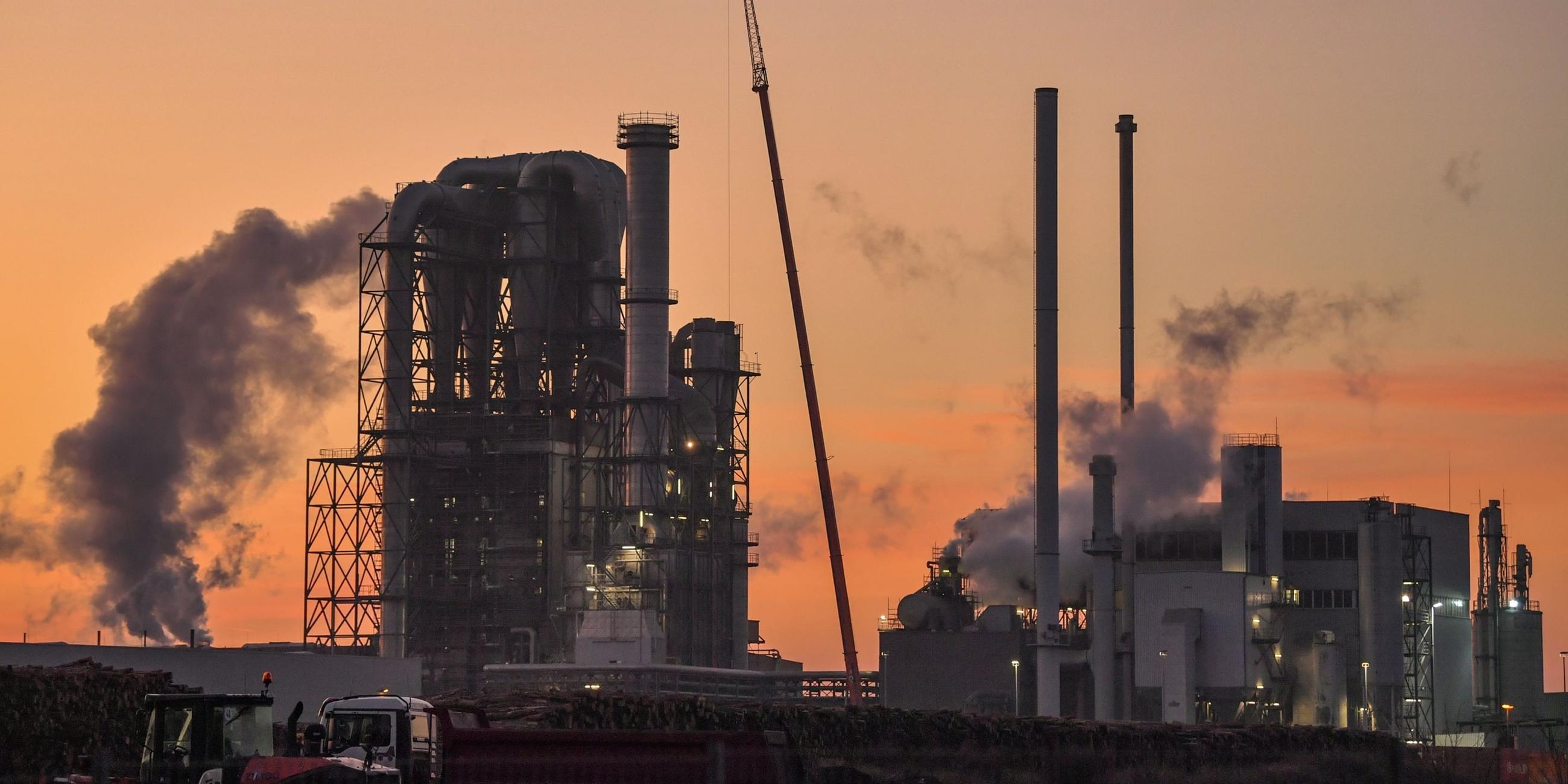 Eine große Industrieanlage mit dampfenden Schornsteinen.