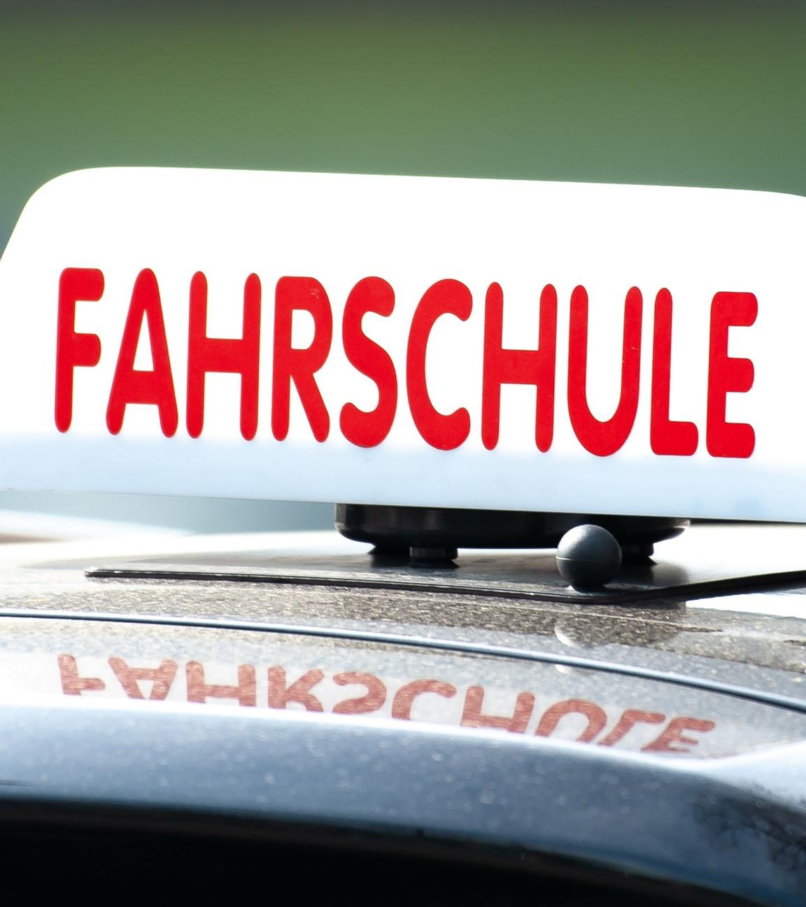 "Fahrschule"-Anzeige auf einem Autodach.